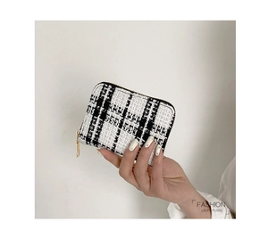 Close-up of black and white tweed coin purse with golden zipper held in hand
