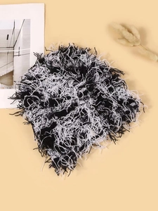 Vista dettagliata del berretto in maglia bianco e nero testurizzato con frange decorative