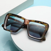 Detail of oversized leopard frame sunglasses with light blue gradient lenses on geometric base