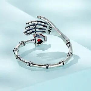 Gothic 925 sterling silver skeleton hand ring holding a red heart gemstone
