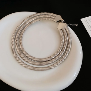 Detailed view of a triple-layered silver snake chain necklace with lobster clasp closure