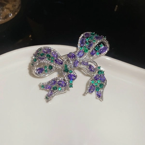 Macro shot of purple and green marquise-cut crystals set in a silver bow brooch detail