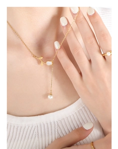 Macro detail of tulip necklace with pearl pendant and matching gold ring for women