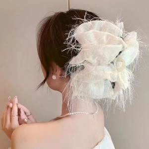 Close-up of white airy mesh cloud hair claw with delicate feathered edges on a bun