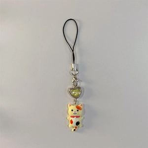 Macro detail of cartoon calico cat charm with heart pendant and durable phone lanyard