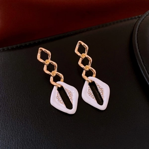 Detailed close-up of vintage-style gold chain earrings with white diamond-set pendants