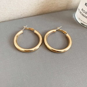 Detailed close-up of polished gold hoop earrings on a textured lifestyle background