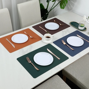 Set of 4 rectangular faux leather placemats in orange, brown, green and blue on marble table