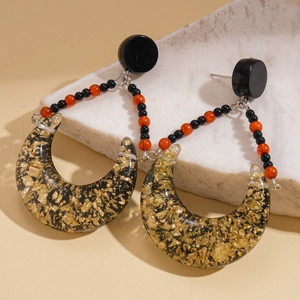Macro detail of crescent resin earrings with gold foil accents on a white stone base