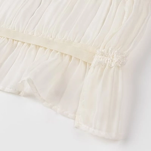 Dettaglio del tessuto in chiffon plissettato bianco e bordo in pizzo delicato