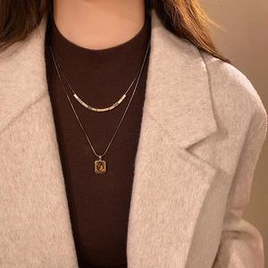 Close-up of 18k gold-plated tiger eye stone necklace styled on a warm winter sweater