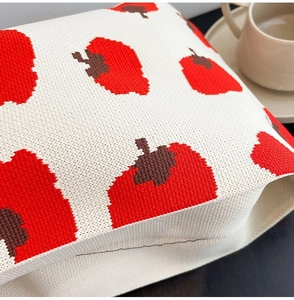 Close-up of knit fabric texture featuring a red chili pattern on a white tote bag