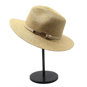 Detail of light beige Panama hat featuring a faux leather band and golden metal buckle