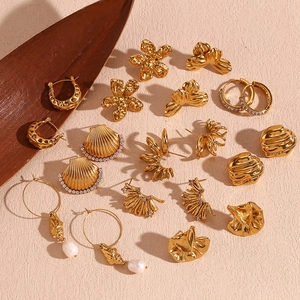 Flat lay of gold vintage geometric earrings with pearls and shells on beige fabric