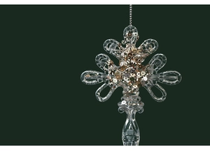 Detail of transparent acrylic Christmas ornament with gold sequins on dark green background