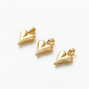 Detailed macro view of three polished 18K gold-plated heart charms for DIY jewelry making