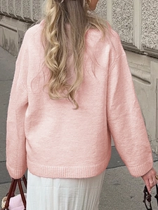 Rückansicht eines lockeren rosa Strickpullovers an einem Model in der Stadtstraße