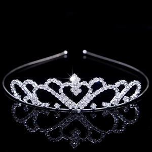 Close-up of silver bridal crown with sparkling rhinestones and heart details on black background