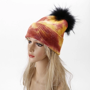 Detail of colorful tie-dye knit beanie with large black faux fur pom pom and ribbed texture