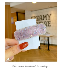 Detail of square candy-colored hair clip with purple rhinestones on a display card