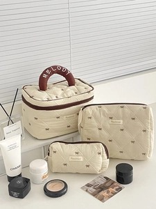 Set di tre pochette per cosmetici trapuntate beige con fiocchi marroni e ricami