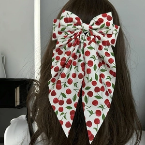 Back view of a model wearing a white bow hair clip with cherry prints and long ribbons