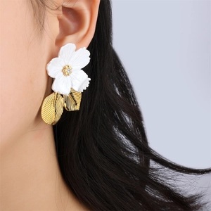 Elegant white resin flower earrings with gold leaves and rhinestones on a female model