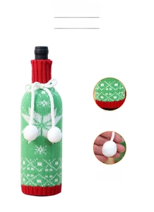 Detail of knitted Christmas wine bottle cover with snowflake patterns and plush pom-poms
