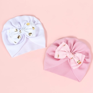 Detail view of pink and white newborn turbans featuring golden polka dot bows