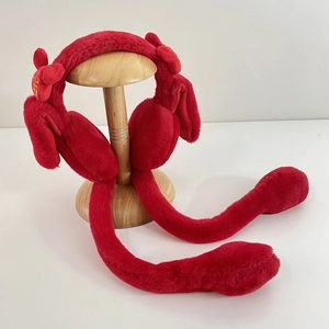 Detail of red plush ear muffs with gold embroidery on a wooden stand display