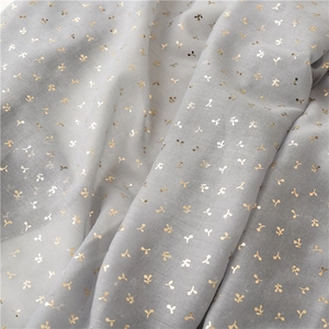 Macro detail of soft grey fabric featuring elegant gold foil leaf patterns and texture