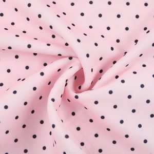 Detailed macro view of pink chiffon fabric with black polka dots in a spiral fold