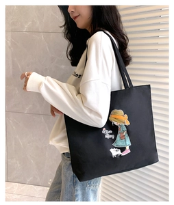 Detail of a large black canvas tote bag with cartoon girl print and Nice Day text