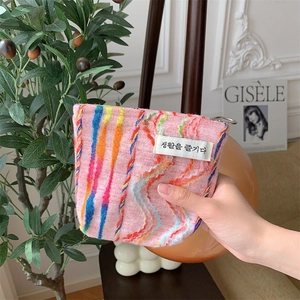 Détail d'une pochette en tricot rose à rayures arc-en-ciel avec étiquette tissée