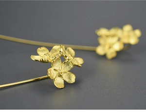 Macro view of gold flower earrings with three detailed blossoms and matte finish