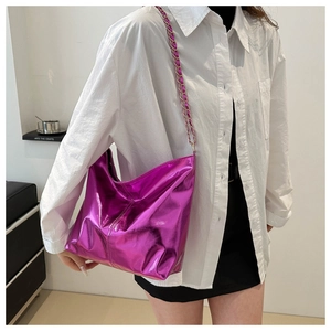 Metallic purple leather tote with elegant chain strap worn by a model in soft lighting