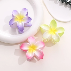 Three-color gradient plumeria flower hair claws in purple, pink, and green on white tray