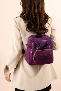 Vue arrière d'un sac à dos violet en nylon porté par un mannequin en manteau beige
