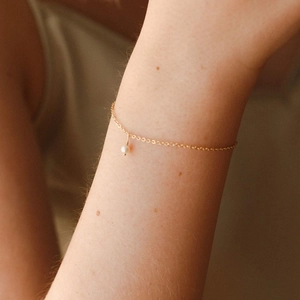 Nahaufnahme eines minimalistischen 14K vergoldeten Edelstahlarmbands mit weißer Perle
