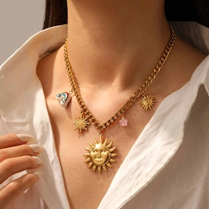 Detail of gold chain necklace with sun face, rainbow cloud and pink star pendants on a model