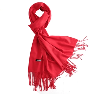 Artfully folded solid red faux cashmere scarf with tassels on white background