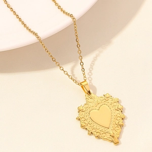 Detailed close-up of a vintage 18k gold heart pendant with intricate floral engravings