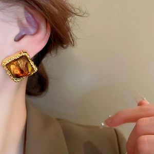 Close-up of vintage resin square stud earrings with textured gold-tone metal frame