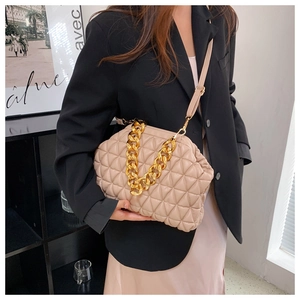 Detail of beige quilted shell bag with gold chain strap and elegant pleated closure
