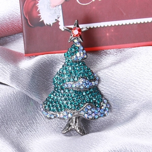 Macro shot of rhinestone Christmas tree brooch featuring green gems and red star accent