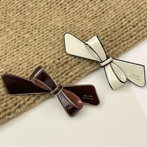 Close-up of French vintage bow hair clips in cream and coffee tones with glossy finish