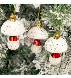 White mushroom Christmas ornament with colorful glitter hanging on a snowy pine branch