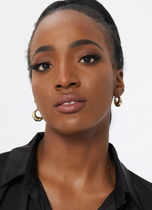 Close-up of polished gold C-shape chunky hoop earrings worn by a model in black shirt