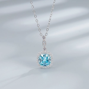Macro shot of a square blue gemstone pendant with halo diamonds on silk background