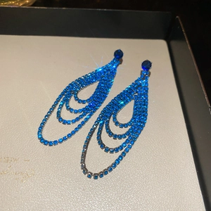 Détail de longues boucles d'oreilles à pampilles en strass bleus dans un écrin de luxe